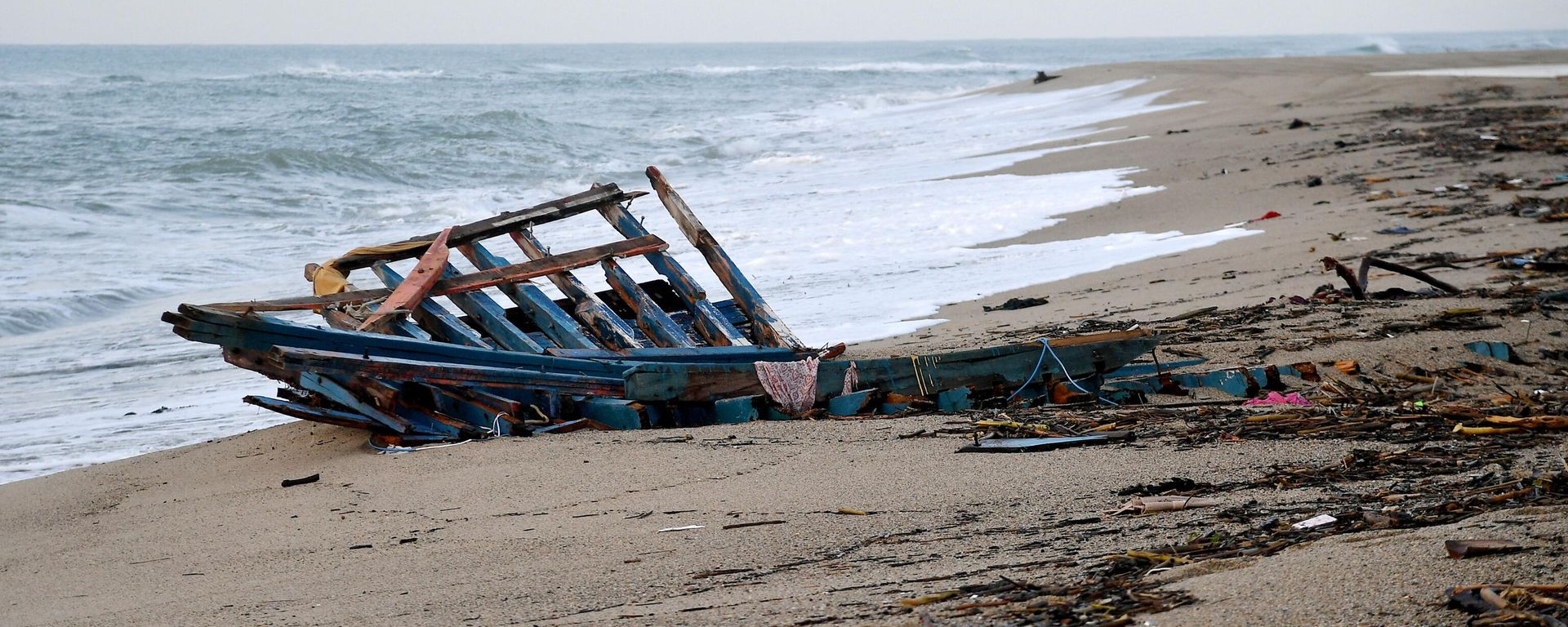 A photograph taken on February 28, 2023 shows parts of a migrants boat, washed on the beach, two day after it sank off Italy's southern Calabria region, in Steccato di Cutro, south of Crotone - Sputnik International, 1920, 07.03.2023