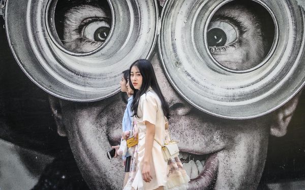 Three young women walk in front of a mural on a street in Bangkok, Thailand. - Sputnik International