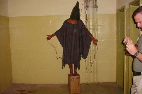 The notorious picture illustrating the "stress position" where a prisoner of war has to stand still or risk receiving high-voltage shocks through the body. This practice was favored by the US army since it leaves almost no trace of violence to the body. - Sputnik International