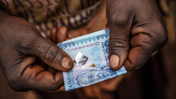 Tanzanian miner Lolesia Limbe folds in a Tanzanian note grains of gold obtained after panning near an open-pit gold mine in Nyarugusu, Geita Region, Tanzania on May 27, 2022.  - Sputnik International