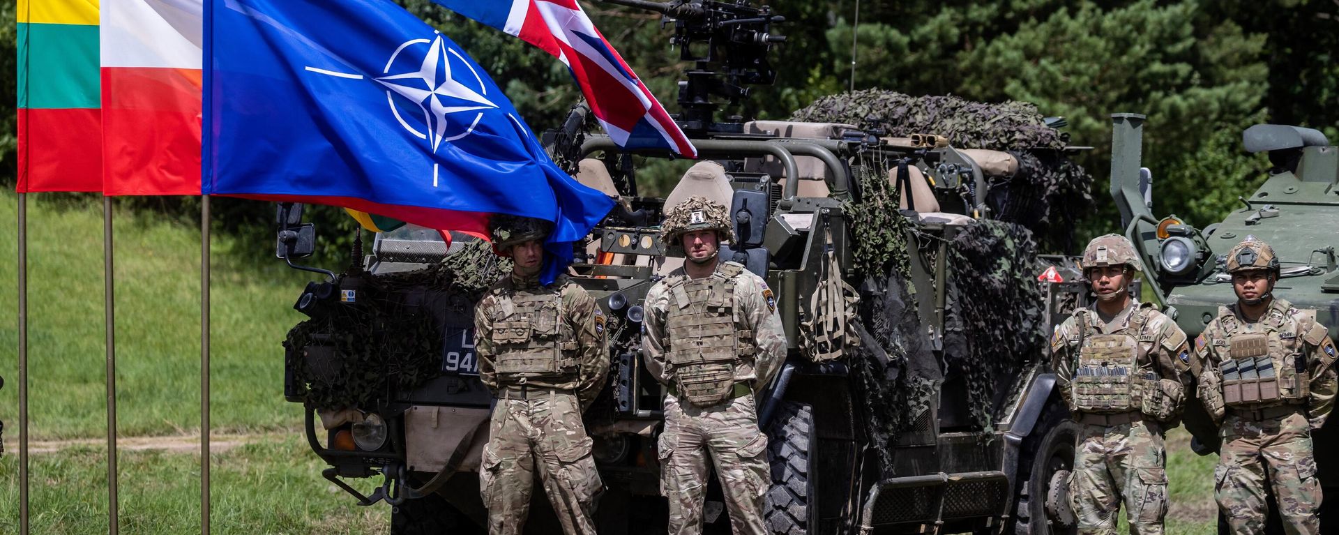 British (L) and US (R) soldiers stand next to a NATO flag on the sidelines of a press conference of the Polish and Lithuanian president on July 7, 2022. - Sputnik International, 1920, 19.03.2023