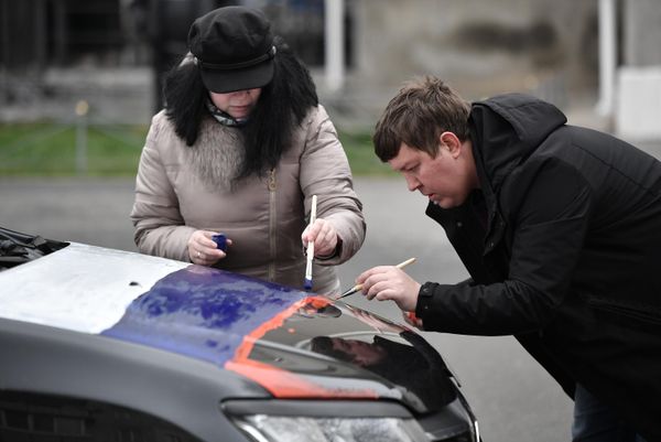 A man and woman paint the hood of a car in the colors of the tricolor at the start of a motor rally dedicated to the 9th anniversary of the reunification of the Republic of Crimea and Sevastopol with Russia in Simferopol. - Sputnik International