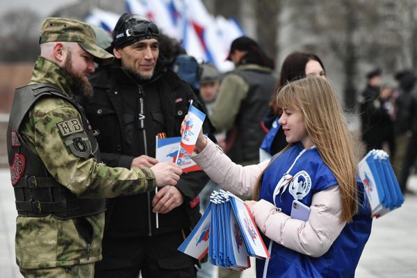 A member of the "Volunteers of Victory" movement hands out flags to participants of a motor rally in Simferopol to mark the 9th anniversary of the reunification of Crimea and Sevastopol with Russia. - Sputnik International