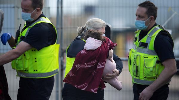 A baby is carried by a UK Border Force officer as migrants are helped ashore after being picked up at sea, at the Marina in Dover, southeast England, on January 4, 2022. - Sputnik International
