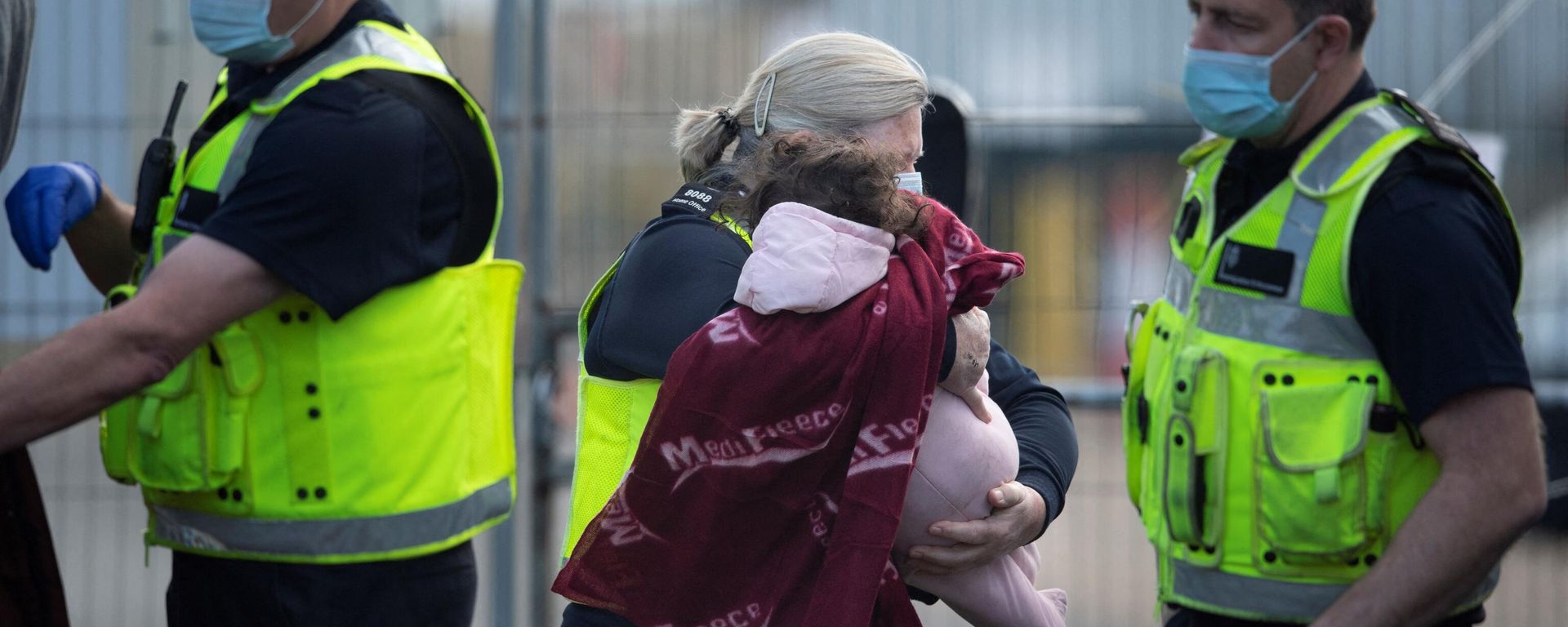 A baby is carried by a UK Border Force officer as migrants are helped ashore after being picked up at sea, at the Marina in Dover, southeast England, on January 4, 2022. - Sputnik International, 1920, 20.03.2023