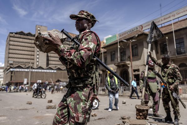 A Kenyan Police officer removes stones that have been used to block a road following clashes with opposition supporters in Nairobi, Kenya on March 20, 2023. - Sputnik International