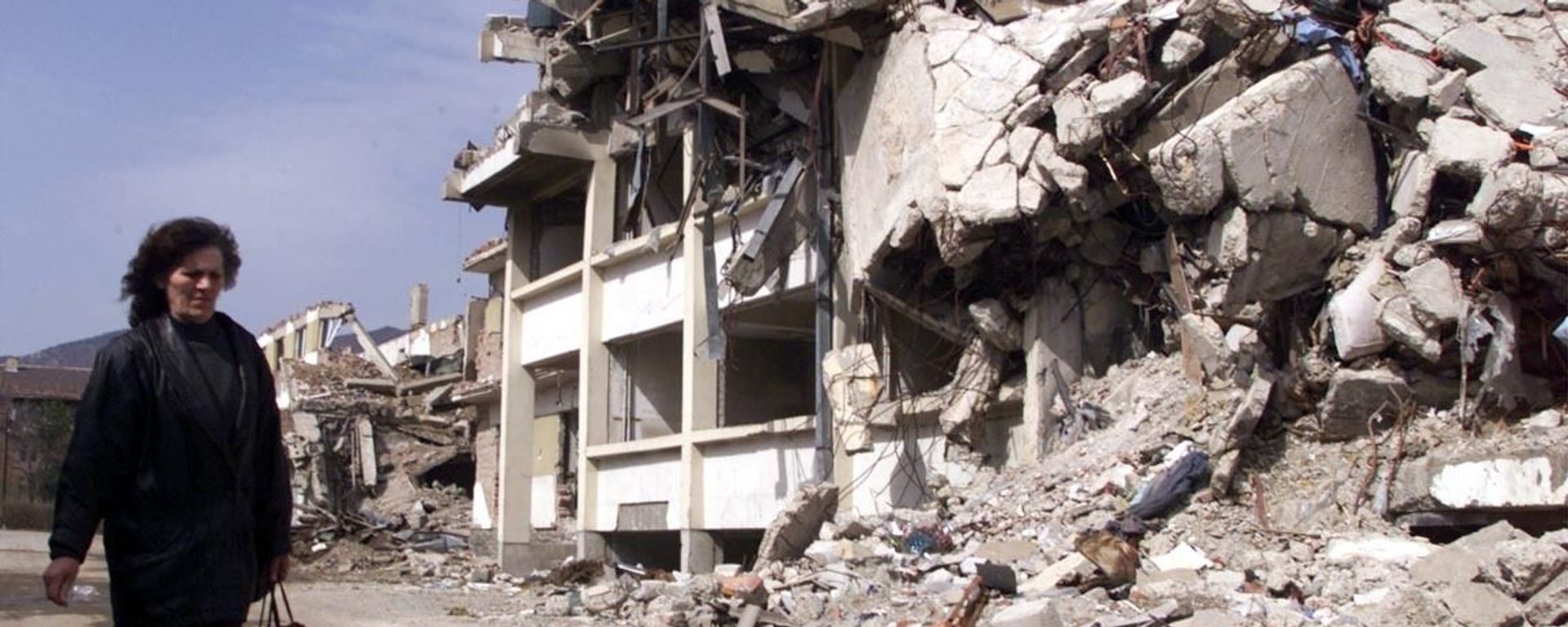 A woman walks past a building destroyed by NATO bombing in Kosovska Mitrovica, Yugoslavia, 1999. - Sputnik International, 1920, 15.09.2023
