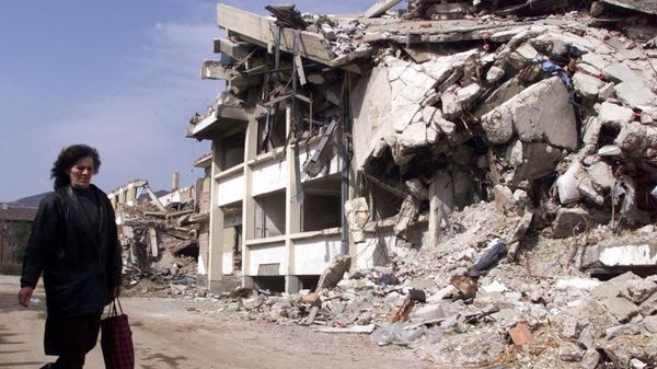A woman walks past a building destroyed by NATO bombing in Kosovska Mitrovica, Yugoslavia, 1999. - Sputnik International