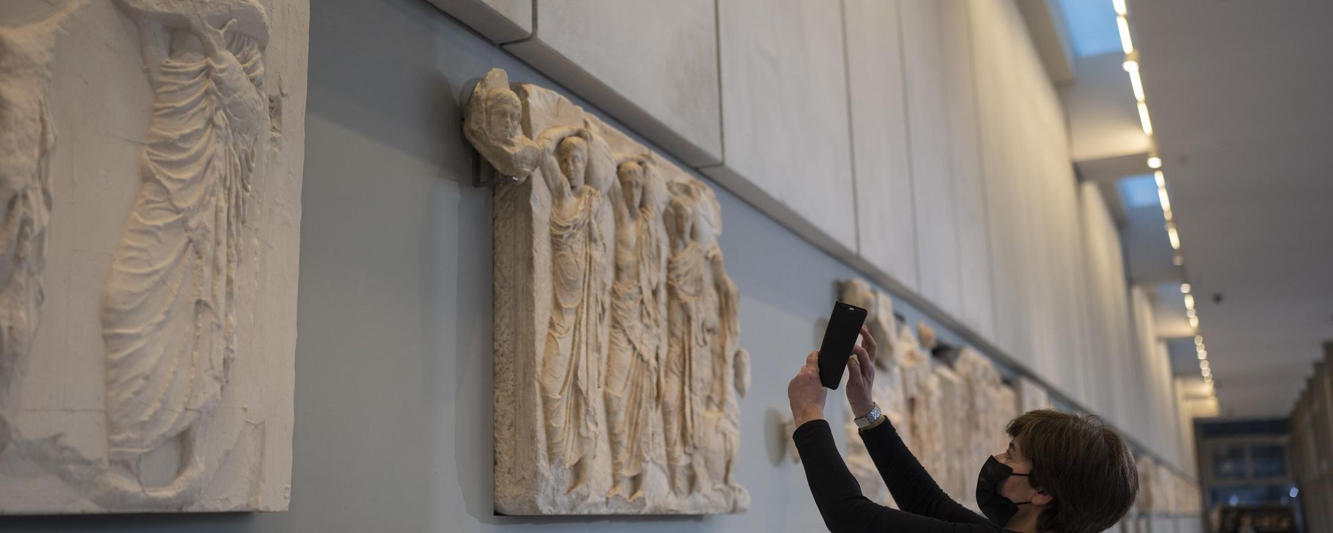 A woman takes a pictures of a newly placed male head on the frieze of the Acropolis museum during a ceremony for the repatriation of three sculpture fragments, in Athens, Friday, March 24, 2023. - Sputnik International, 1920, 25.08.2023