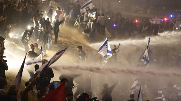 Israeli police use a water cannon to disperse demonstrators blocking a highway during a protest against plans by Prime Minister Benjamin Netanyahu's government to overhaul the judicial system in Tel Aviv, Israel, Monday, March 27, 2023. - Sputnik International