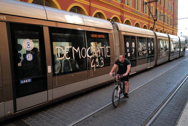 A man cycles past a message that reads, 'Democracy 49.3', daubed on the side one a tram carriage as demonstrations take place across France.  - Sputnik International