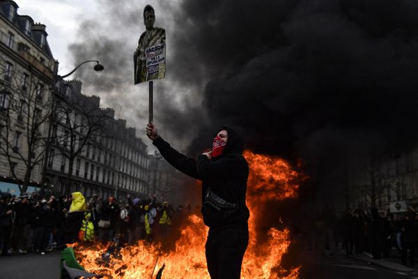 A protester holds a portrait of French President Emmanuel Macron next to a fire ready to burn it.  - Sputnik International