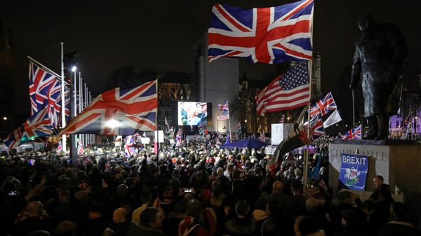 A Brexit supporter waves a US and Union flags as they wait for the festivities to begin in Parliament Square, the venue for the Leave Means Leave Brexit Celebration in central London on January 31, 2020, the day that the UK formally leaves the European Union - Sputnik International