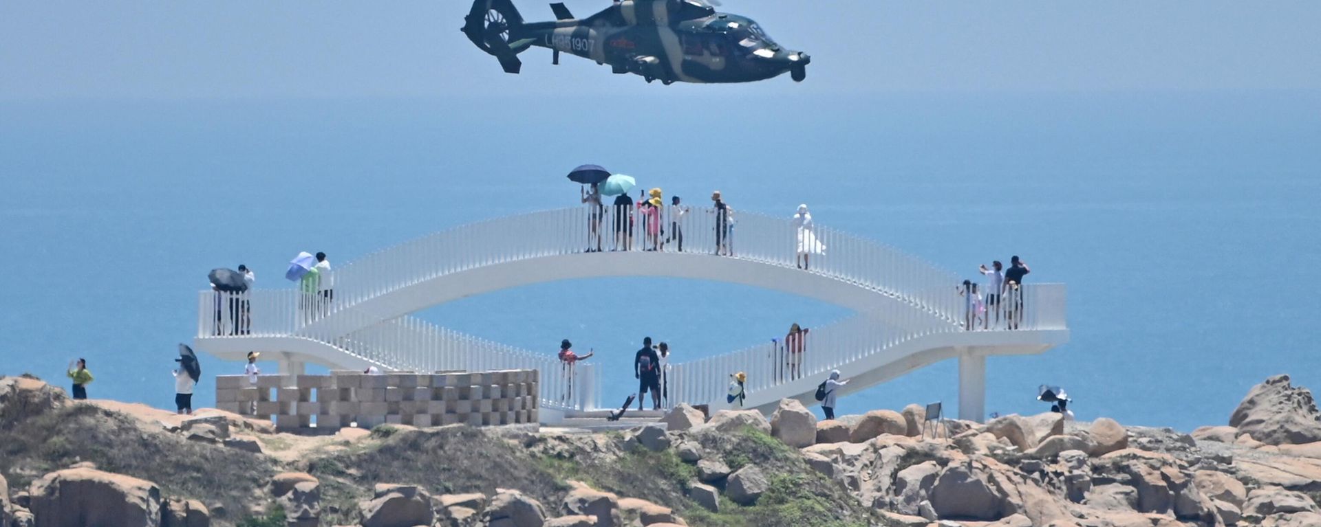 Tourists look on as a Chinese military helicopter flies past Pingtan island, one of mainland China's closest point from Taiwan, in Fujian province on August 4, 2022 Tourists look on as a Chinese military helicopter flies past Pingtan island, one of mainland China's closest point from Taiwan, in Fujian province on August 4, 2022 - Sputnik International, 1920, 10.04.2023