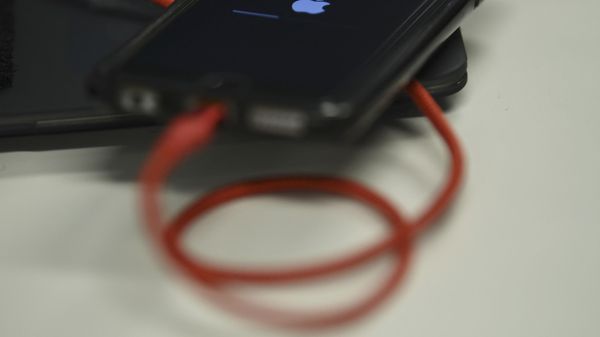 An iPhone 6S is plugged into a battery charger. - Sputnik International