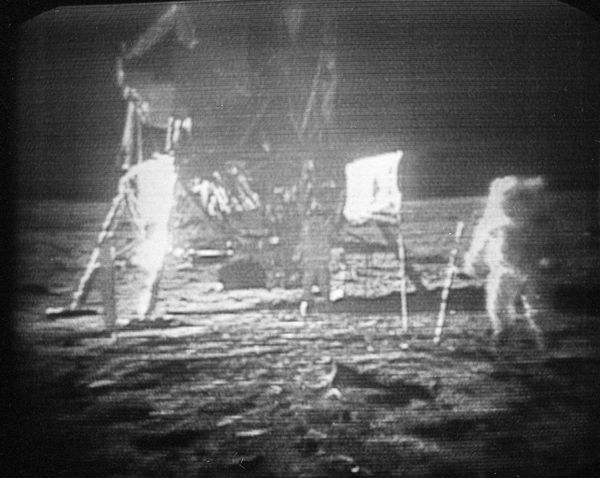 Apollo 11 astronaut Neil Armstrong, right, trudges across the surface of the Moon, leaving behind footprints, July 20, 1969. The US flag, planted on the surface by the astronauts, can be seen between Armstrong and the lunar module. Edwin E. Aldrin is seen closer to the craft. The men said the surface of the Moon was like soft sand and that they left footprints several inches deep wherever they walked. - Sputnik International
