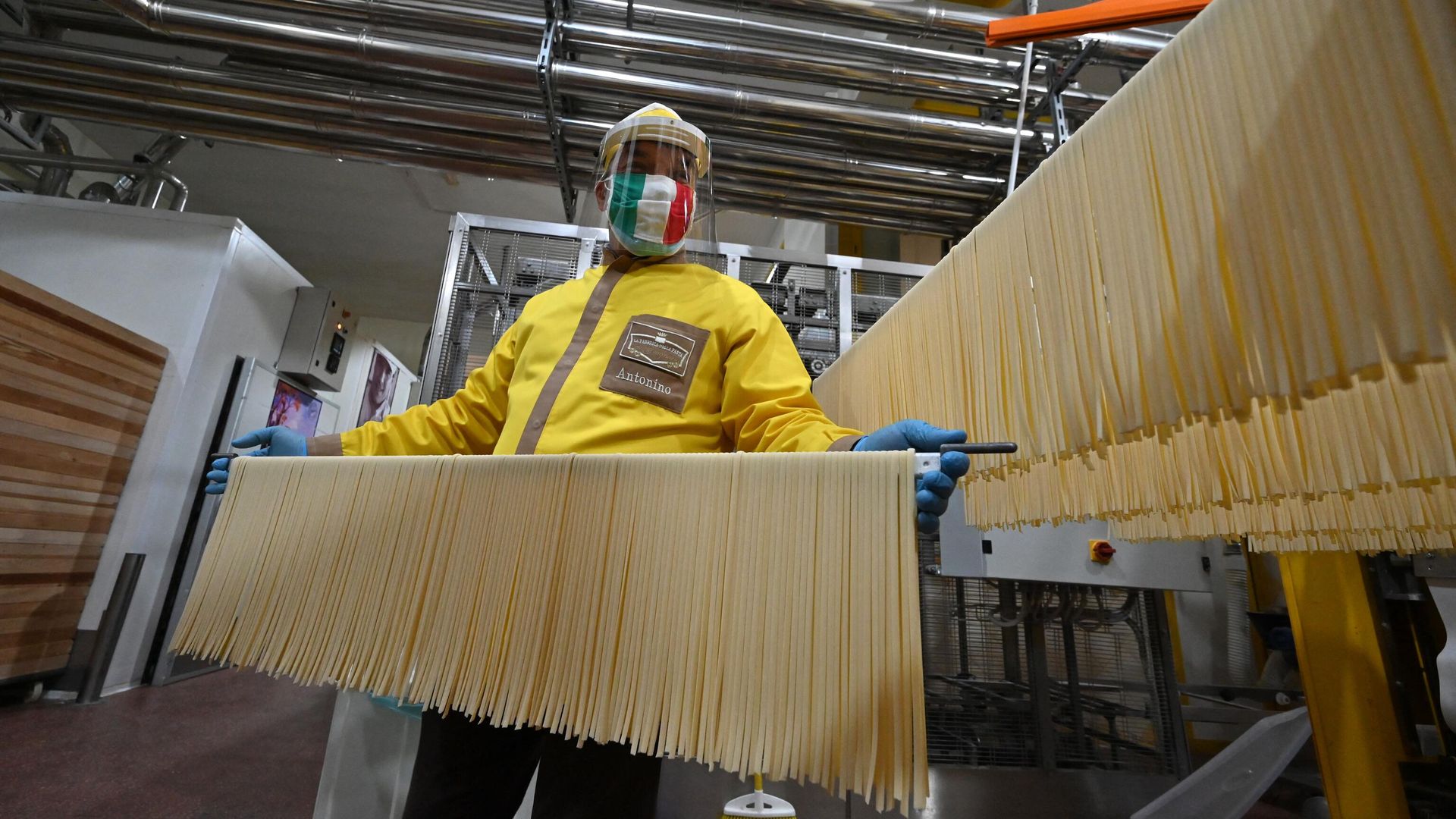 Co-owner with his three brothers and production manager of the Pasta di Gragnano factory near Naples, Antonino Moccia, wearing a face mask in the colors of the Italian flag, processes tagliatelle pasta at the production line on April 24, 2020. - Sputnik International, 1920, 05.05.2023