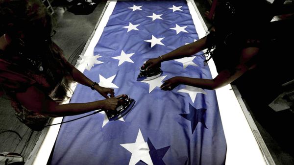Employees Lottie Penick, left, and Melissa Hodnett iron stars onto a United States flag at Annin Flagmakers in South Boston, Va. File photo. - Sputnik International