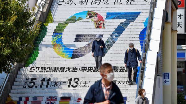 People walk down stairs displaying the logo of the upcoming G7 Finance Ministers and Central Bank Governors' Meeting at Niigata railway station in Niigata on May 10, 2023 - Sputnik International