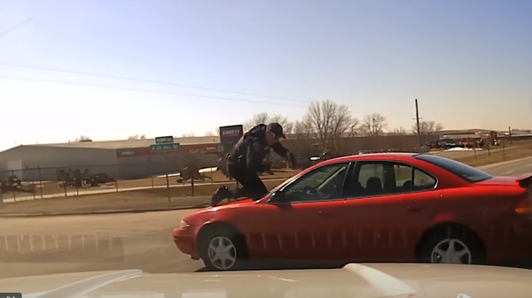 Officer Patrick McCarty trying to stop Dennis Guider Jr. while on the car's hood. - Sputnik International