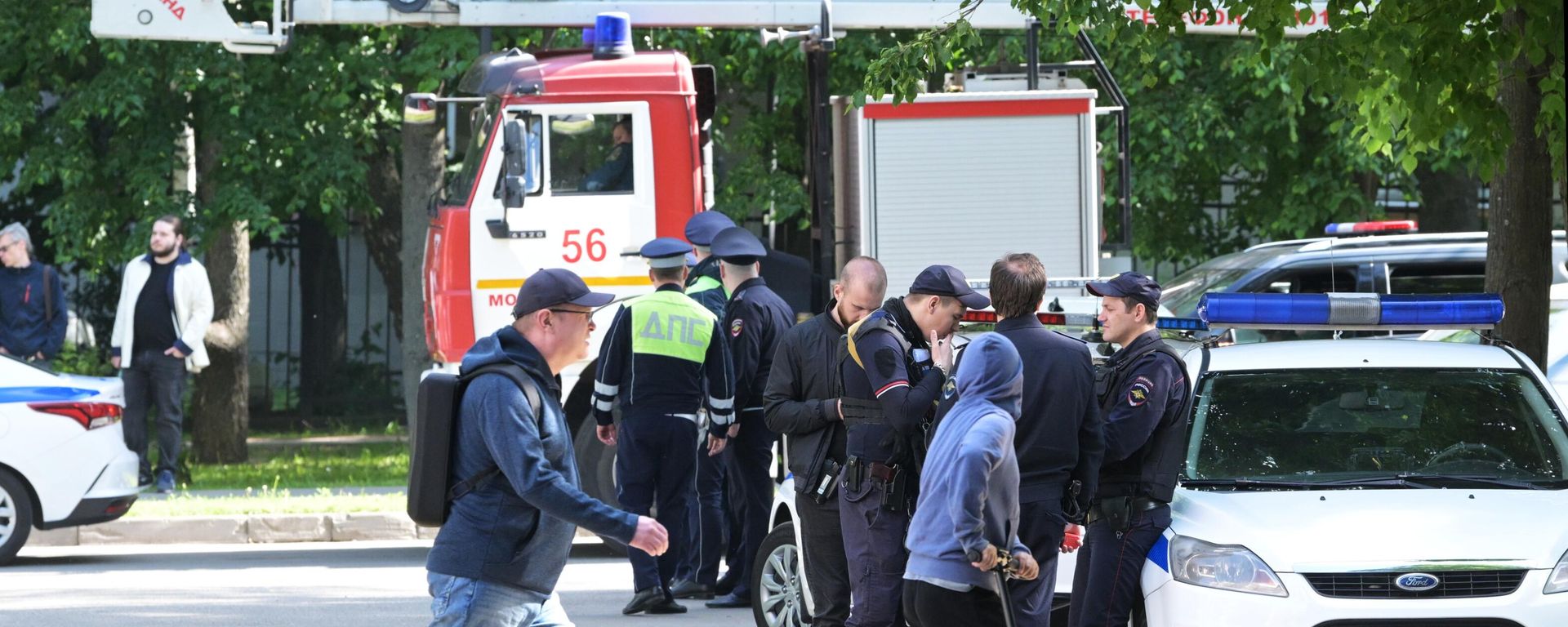 People walk past emergency personnel outside a residential building damaged in a drone attack in Moscow - Sputnik International, 1920, 30.05.2023