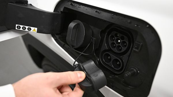 A man shows a charging connector in an electric car  - Sputnik International