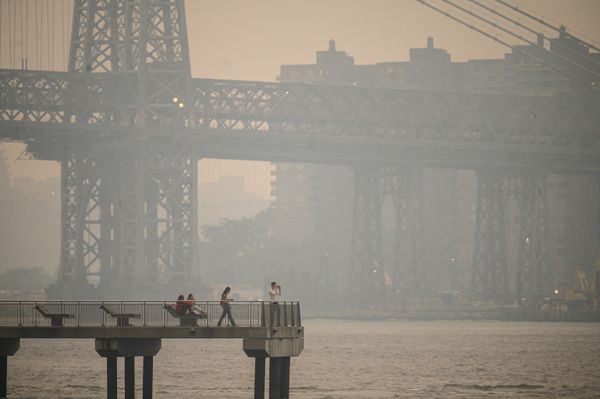 People stand on a pier before the New York City skyline and East River veiled in smoke in Brooklyn on June 6, 2023. Smoke from the wildfires blazing in eastern Canada has drifted south. Hundreds of wildfires were burning in Canada on June 6, 2023. The Canadian Interagency Forest Fire Center said that Quebec alone had over 150 active blazes across the province. - Sputnik International