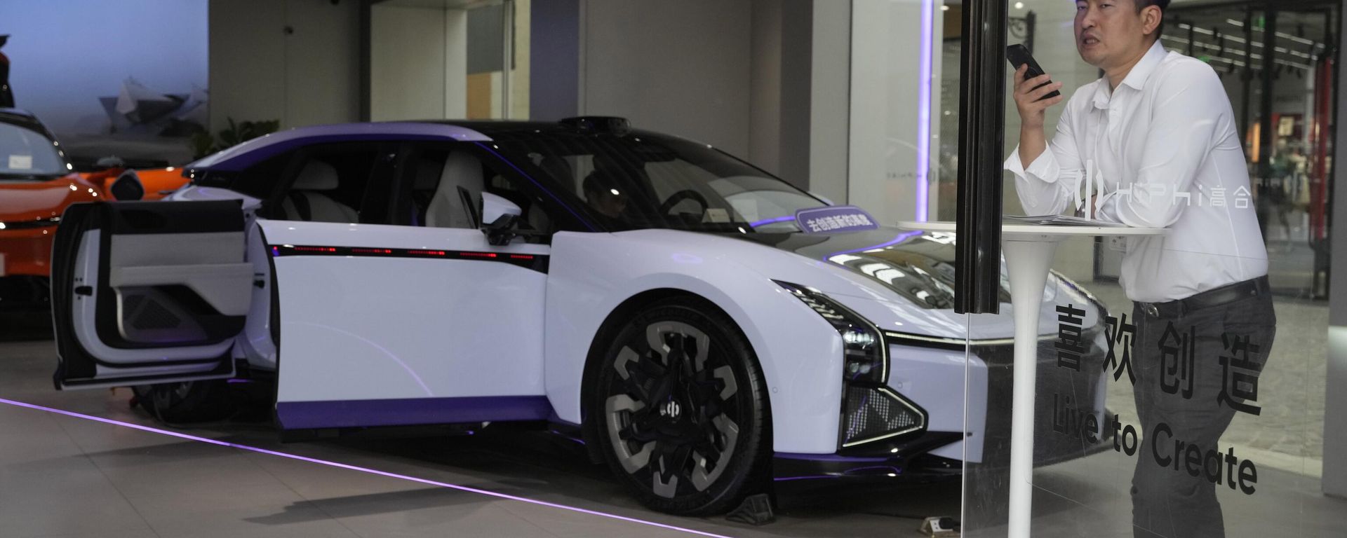 A man talks on his phone near an electric car from Chinese automaker HiPhi at a showroom in Beijing, Thursday, April 13, 2023. Global and Chinese automakers plan to unveil more than a dozen new electric SUVs, sedans and muscle cars this week at the Shanghai auto show, their first full-scale sales event in four years in a market that has become a workshop for developing electrics, self-driving cars and other technology. - Sputnik International, 1920, 16.01.2024