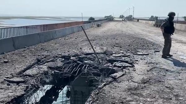 A Russian Investigative Committee serviceman stands on a bridge damaged during the Ukrainian armed forces' attack, on the administrative border between the Kherson Region and the Crimea near the village of Chongar, Crimea, Russia.  - Sputnik International
