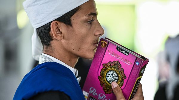 A religious Muslim student kissing a copy of the holy Quran while observing Nuzul Quran. - Sputnik International