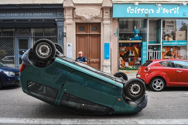 A police officer stands by a car which is upside down on a street following a fourth consecutive night of rioting in France.  - Sputnik International
