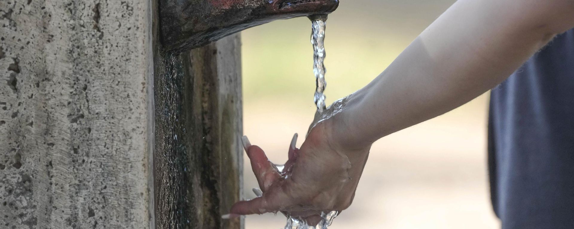 A woman puts her hand under water flowing from a fountain with a she-wolf head in Rome, Friday, July 14, 2023. An intense heat wave has reached Italy, bringing temperatures close to 40 degrees Celsius in many cities across the country.  - Sputnik International, 1920, 14.07.2023