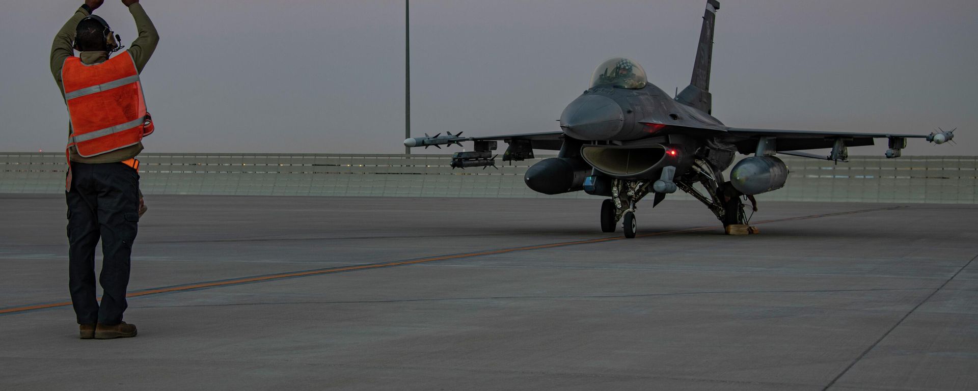 In this handout photo from the U.S. Air Force, an airman guides an F-16 Fighting Falcon during training at Al-Udeid Air Base, Qatar in January 2022. File photo. - Sputnik International, 1920, 06.03.2026