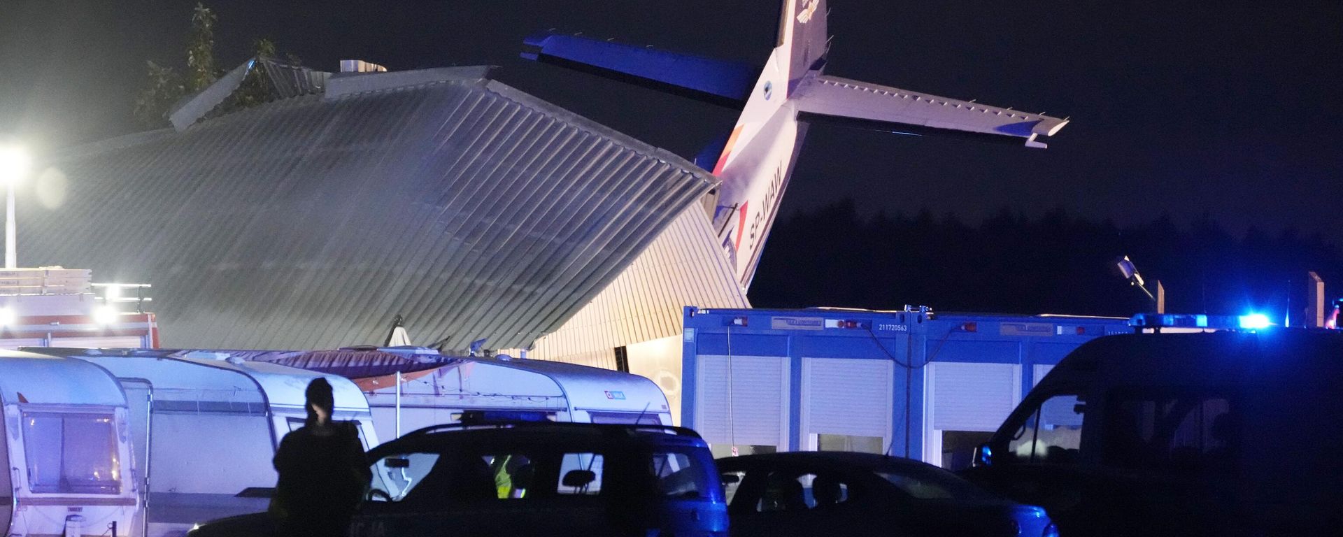 The tail of a Cessna 208 plane sticks out of a hangar after it crashed there in bad weather killing several people and injuring others, at a sky-diving centre in Chrcynno, central Poland, on Monday, July 17, 2023.  - Sputnik International, 1920, 18.07.2023