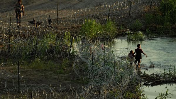 A Texas trooper talks with migrants as they walk along concertina wire and try to cross the Rio Grande at the Texas-U.S. border in Eagle Pass , Texas, Thursday, July 6, 2023 - Sputnik International