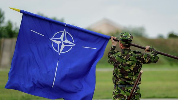 A Romanian serviceman furls the NATO flag. File photo - Sputnik International