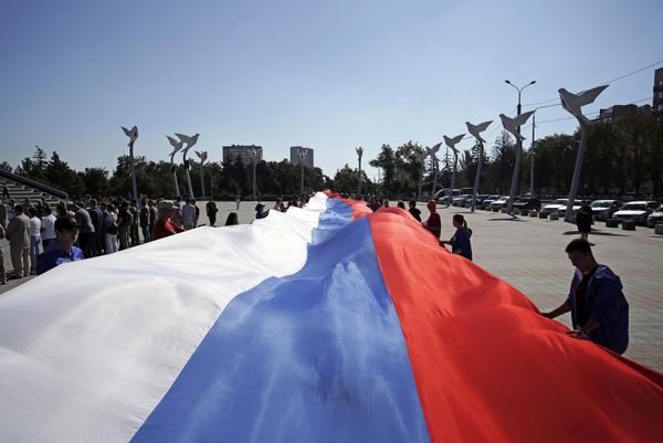 Participants in celebrations marking Russian Flag Day unfurl a 100-metre-long Russian flag on Lenin Square in Mariupol. - Sputnik International