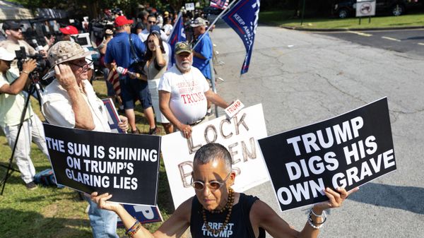 A counter protester waves anti-Trump signs outside the Fulton County Jail ahead of his expected arrival on August 24, 2023, in Atlanta, Georgia. Former US President Donald Trump and 18 others were given until August 25, 2023 to surrender at the courthouse after being indicted on 41 counts related to their efforts to overturn the 2020 US Presidential election. (Photo by Christian MONTERROSA / AFP) - Sputnik International