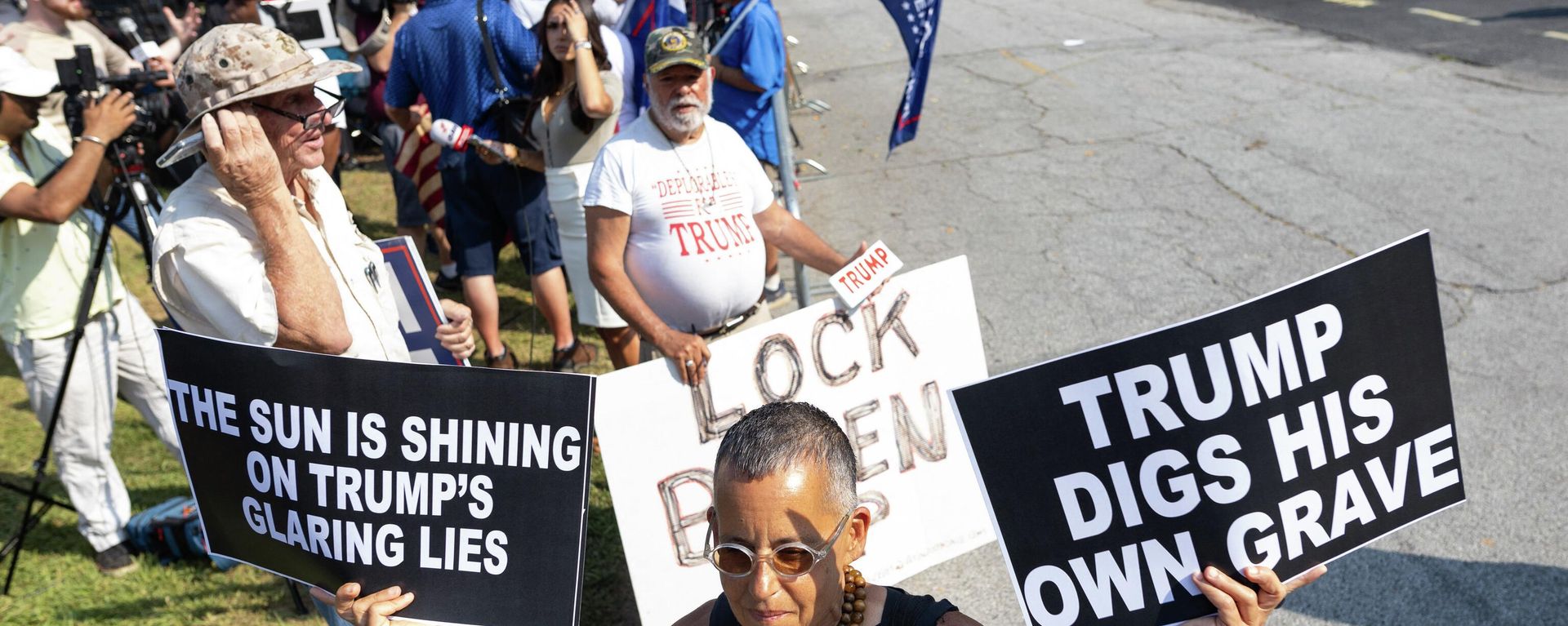 A counter protester waves anti-Trump signs outside the Fulton County Jail ahead of his expected arrival on August 24, 2023, in Atlanta, Georgia. Former US President Donald Trump and 18 others were given until August 25, 2023 to surrender at the courthouse after being indicted on 41 counts related to their efforts to overturn the 2020 US Presidential election. (Photo by Christian MONTERROSA / AFP) A counter protester waves anti-Trump signs outside the Fulton County Jail ahead of his expected arrival on August 24, 2023, in Atlanta, Georgia. Former US President Donald Trump and 18 others were given until August 25, 2023 to surrender at the courthouse after being indicted on 41 counts related to their efforts to overturn the 2020 US Presidential election. (Photo by Christian MONTERROSA / AFP) - Sputnik International, 1920, 26.08.2023