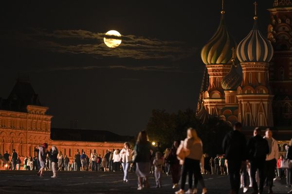 The August Super Blue Moon sets behind a historical building and the St. Basil's Cathedral, right, as people walk in Red Square in Moscow, Russia, Wednesday, Aug. 30, 2023. - Sputnik International