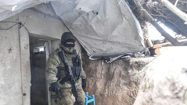 A Russian serviceman leaves a bunker in a trench at a position in the special military operation zone - Sputnik International