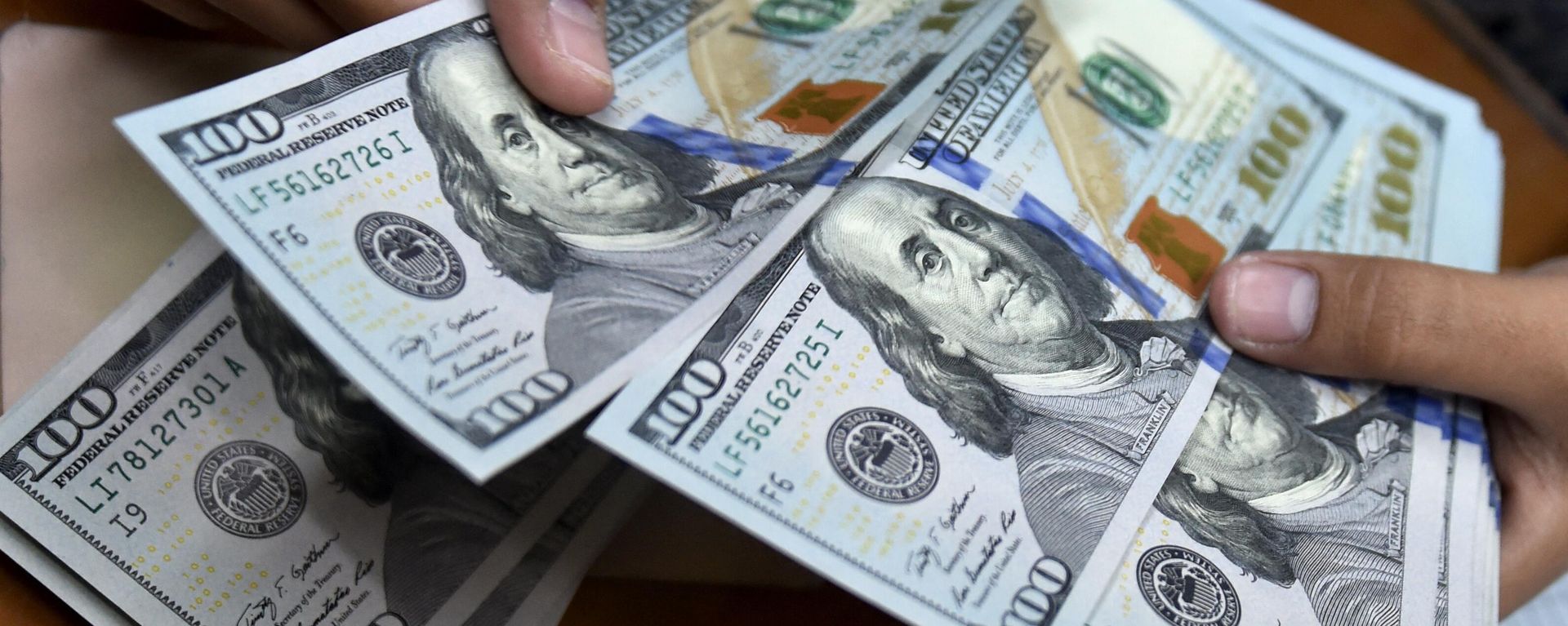 A money changer counts US dollar banknotes for customers. - Sputnik International, 1920, 15.09.2023