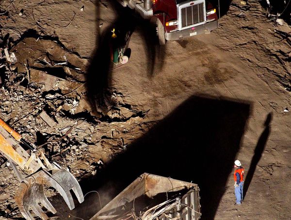 A worker looks on as a crane moves debris from the remains of the World Trade Center complex in New York City into a truck. - Sputnik International