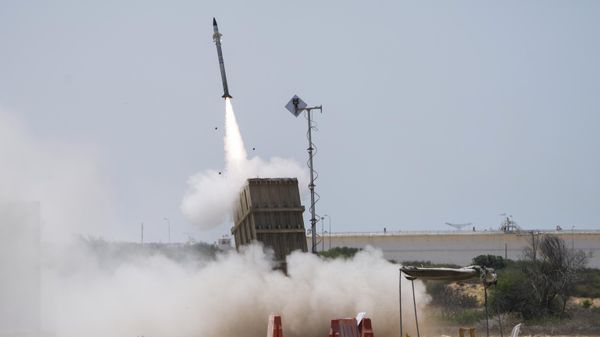 An Israeli soldier takes cover as an Iron Dome air defence system launches to intercept a rocket fired from the Gaza Strip, in Ashkelon, southern Israel, Sunday, Aug. 7, 2022.  - Sputnik International