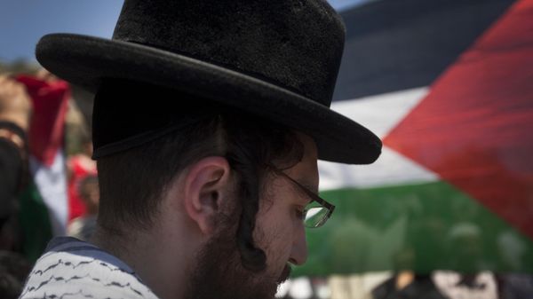 A Palestinian flag flutter in the background as a member of Neturei Karta attends a protest with Palestinian youths in the Arab east Jerusalem neighbourhood of Silwan. File photo. - Sputnik International