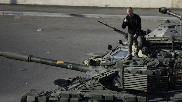 A man poses for pictures on a captured Ukrainian tank in Lugansk - Sputnik International
