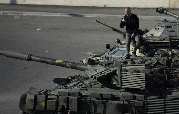 A visitor poses for pictures on top of a captured Ukrainian tank. - Sputnik International