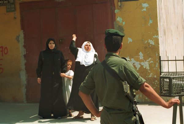 An Arab woman screams abuse at an armed Israeli border policeman after her son was arrested this morning in curfewed Gaza Strip, Occupied Gaza Strip, for hurling stones at troops, May 21, 1990.During that time, the Gaza Strip was under Israeli military occupation as part of the broader Palestine-Israel conflict. The Israeli military had imposed curfews and various restrictions on the movement of Palestinians in the area, as part of their efforts to maintain control and security in the region.Palestinians throwing rocks at Israeli soldiers were often during that time and were often expressions of frustration, anger, and resistance to Israeli military presence and control. The throwing of stones was seen as a symbol of Palestinian resistance, particularly among Palestinian youth.It was common for Palestinian stone-throwers to face arrest by Israeli security forces. The response to such incidents often included arrests, detentions, and sometimes more severe measures, depending on the circumstances and the severity of the protest.Overall, such incidents reflect the tense and challenging environment in the Gaza Strip during the period of Israeli occupation, where confrontations between Palestinian residents and Israeli forces were relatively common forms of protest and resistance. An Arab woman screams abuse at an armed Israeli border policeman after her son was arrested this morning in curfewed Gaza Strip, Occupied Gaza Strip, for hurling stones at troops, May 21, 1990.During that time, the Gaza Strip was under Israeli military occupation as part of the broader Palestine-Israel conflict. The Israeli military had imposed curfews and various restrictions on the movement of Palestinians in the area, as part of their efforts to maintain control and security in the region.Palestinians throwing rocks at Israeli soldiers were often during that time and were often expressions of frustration, anger, and resistance to Israeli military presence and control. The throwing of stones was seen as a symbol of Palestinian resistance, particularly among Palestinian youth.It was common for Palestinian stone-throwers to face arrest by Israeli security forces. The response to such incidents often included arrests, detentions, and sometimes more severe measures, depending on the circumstances and the severity of the protest.Overall, such incidents reflect the tense and challenging environment in the Gaza Strip during the period of Israeli occupation, where confrontations between Palestinian residents and Israeli forces were relatively common forms of protest and resistance. - Sputnik International