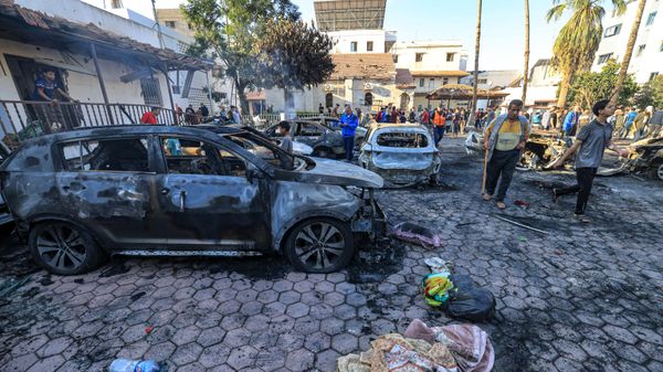 People gather near destroyed vehicles at the site of the Ahli Arab hospital in central Gaza on October 18, 2023 in the aftermath of an overnight blast there.  - Sputnik International
