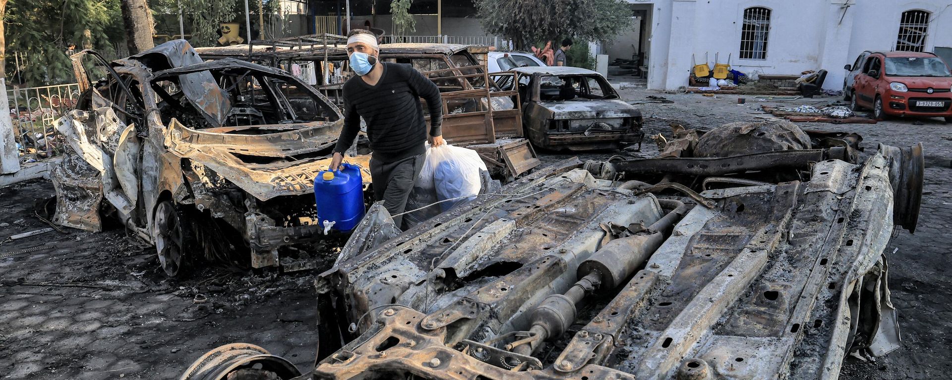 A man walks with salvaged items past destroyed vehicles at the site of the Ahli Arab hospital in central Gaza on October 18, 2023 in the aftermath of an overnight strike there. A man walks with salvaged items past destroyed vehicles at the site of the Ahli Arab hospital in central Gaza on October 18, 2023 in the aftermath of an overnight strike there. - Sputnik International, 1920, 20.10.2023